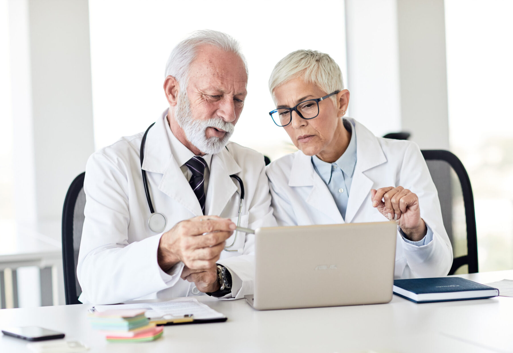 Deux professionnels de santé échangent en consultant des informations sur l'écran d'un ordinateur